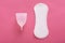 Sanitary pad and menstrual cup isolated over pink background in studio, choosing best method of hygiene, Concept of critical days