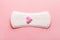 Sanitary pad with pink woolen heart as blood drop on pastel rose background, menstruation cycle, intimate hygiene