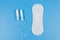 Sanitary pad and tampons on blue background. Top view