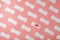 Sanitary pads on a pink background in the form of a diagonal pattern of repetitions, with a red flower on the pad