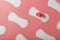 Sanitary pads on a pink background in the form of a diagonal pattern of repetitions, with a red flower on the pad