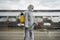 Sanitation worker in hazmat protection suit and N95 mask with chemical decontamination sprayer tank.Disinfecting streets and