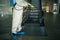 Sanitizing worker disinfects the escalator with a spray at the empty shopping mall to prevent the covid-19 spread in public places