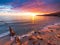 Sanremo, Riviera dei Fiori, Liguria, Italy. Scenis rocks and pebbles on beach illuminated beautiful by sunset light. Dramatic
