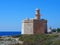 Sant Nicolau Castle in ciutadella menorca on the cliffs with blue summer sea and the lighthouse in the distance