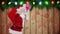 Santa carrying sack of gifts against festive wooden background