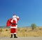 Santa claus with bag full of presents standing on an open road a