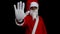 Santa claus on black background with serious face raises his arm and makes the stop sign with his hand.