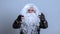 Santa Claus in a black biker jacket and gloves points his fingers forward and looks at the camera. Evil emotion concept. A long-