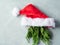 Santa Claus cap with fir tree branches as beard on gray background, minimal christmas concept