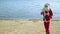 Santa Claus carries a gift bag along the ocean or lake