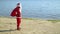 Santa Claus carries a gift bag along the sea or lake