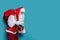 santa claus carrying huge red sack of gifts on blue background while holding gift box in his hand.
