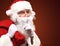 Santa Claus carrying huge red sack and showing gesture of silence