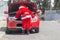 Santa Claus checking his car engine in front of his car that is damaged on Christmas