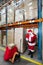 Santa claus checking list of gifts in storehouse