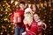 Santa Claus and child boy and girl posing together indoor near decorated xmas tree with lights, they talking, smiling and