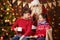 Santa Claus and child boy and girl posing together indoor near decorated xmas tree with lights, they talking, smiling and