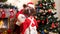 Santa Claus with a child decorates a Christmas tree in the room with the Christmas decorations.