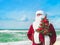 Santa Claus with decorated christmas tree on tropical sea beach