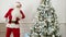 Santa Claus doing funny robot dance next to the Christmas tree