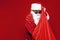 santa claus in festive glasses and hat takes out gifts from bag on red background, greedy man in santa costume