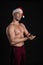 Santa Claus. Fitness beatseps demonstrates abs cubes, makes everyone fall in love on a black background In a red cap, on New Year