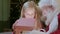 Santa Claus gives gift magic box girl, bright light shines from box to little blonde girl sitting in chair in room with