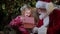 Santa Claus gives gift magic box girl, bright light shines from box to little blonde girl sitting in chair in room with