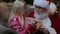 Santa Claus gives gift magic box girl, bright light shines from box to little blonde girl sitting in chair in room with