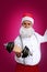 Santa Claus in glasses, in a white shirt, shakes muscles with dumbbells, Christmas and sports concept, close-up