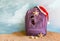 Santa Claus hat on backpack standing on sand beach.