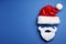 Santa Claus hat and beard on blue background, flat lay