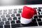 Santa Claus Hat on laptop keyboard. Searching lockation online for Christmas celebration
