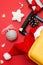 Santa Claus hat lies in yellow suitcase, christmas baubles and gift on red background. Concept: tourist trips, vacation, travel