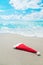 Santa Claus hat on seashore against waves