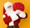 Santa Claus holding big red sack on his back on orange