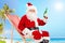 Santa Claus holding a bottle of beer on a beach