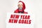 Santa Claus is holding a sign with the inscription - NEW YEAR NEW GOALS