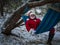 Santa Claus lies relaxed in the hammock in the winter forest