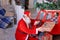 Santa Claus makes thumbs up working with laptop and little girl