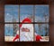Santa Claus peeking in window making Shh sign, finger to mouth, with snowy winter scene in the background