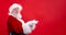 Santa Claus pointing aside empty copy space on finger and looking showing blank place for advertised product or text on
