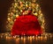 Santa Claus Red Bag full with Toy Gifts, Christmas Presents. Christmas Sack tied by Golden Bow Ribbon over Decorated lightening