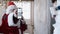 Santa Claus in red costume shows QR code before visiting the Christmas party