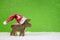 Santa Claus with red hat - wooden deer on green christmas background.