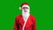 Santa Claus in red suit pointing aside on green chroma key background