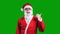 Santa Claus in red suit pointing aside on green chroma key background