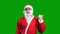 Santa Claus in red suit pointing aside on green chroma key background