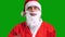 Santa Claus in red suit pointing aside on green chroma key background